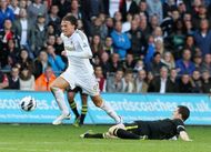 Michu (L) of Swansea avoids a tackle by Wigan's Gary Caldwell